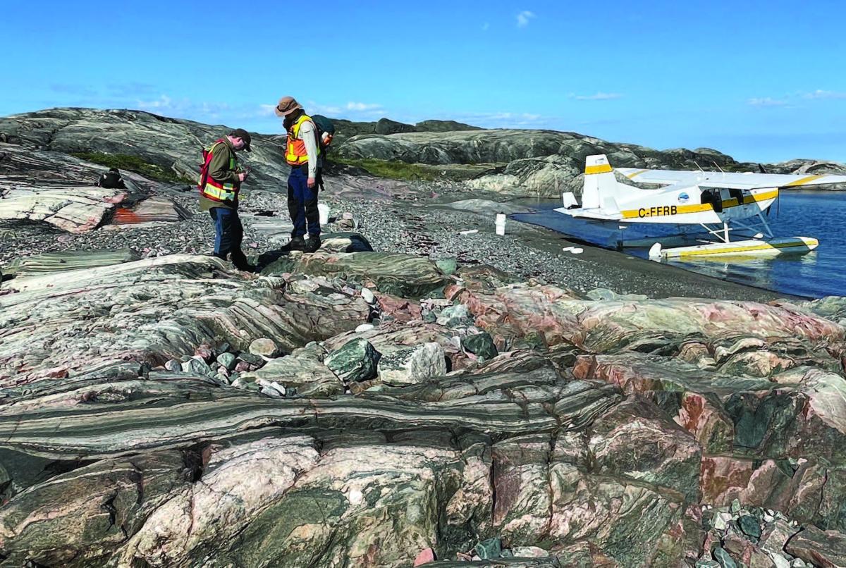 men standing on rocks with biplane in background